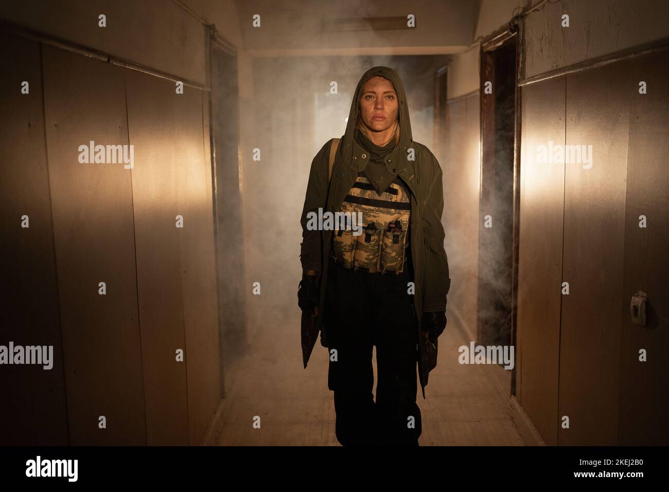 Brave female soldier walking in a polluted post apocalyptic abandoned building with smog: environmental disaster and apocalypse Stock Photo