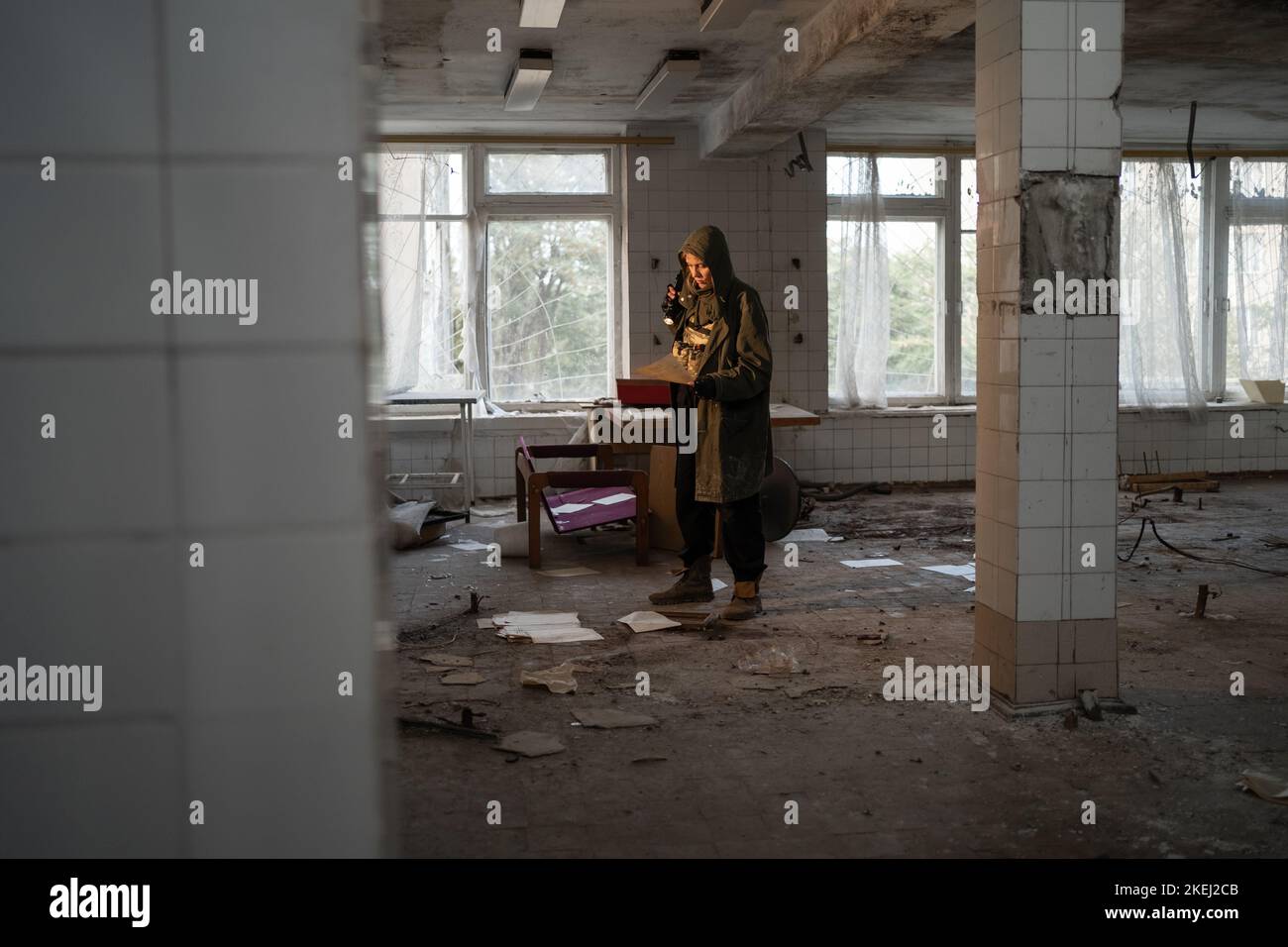 Nuclear post apocalypse life after doomsday concept. Grimy female survivor reading in abandoned building Stock Photo