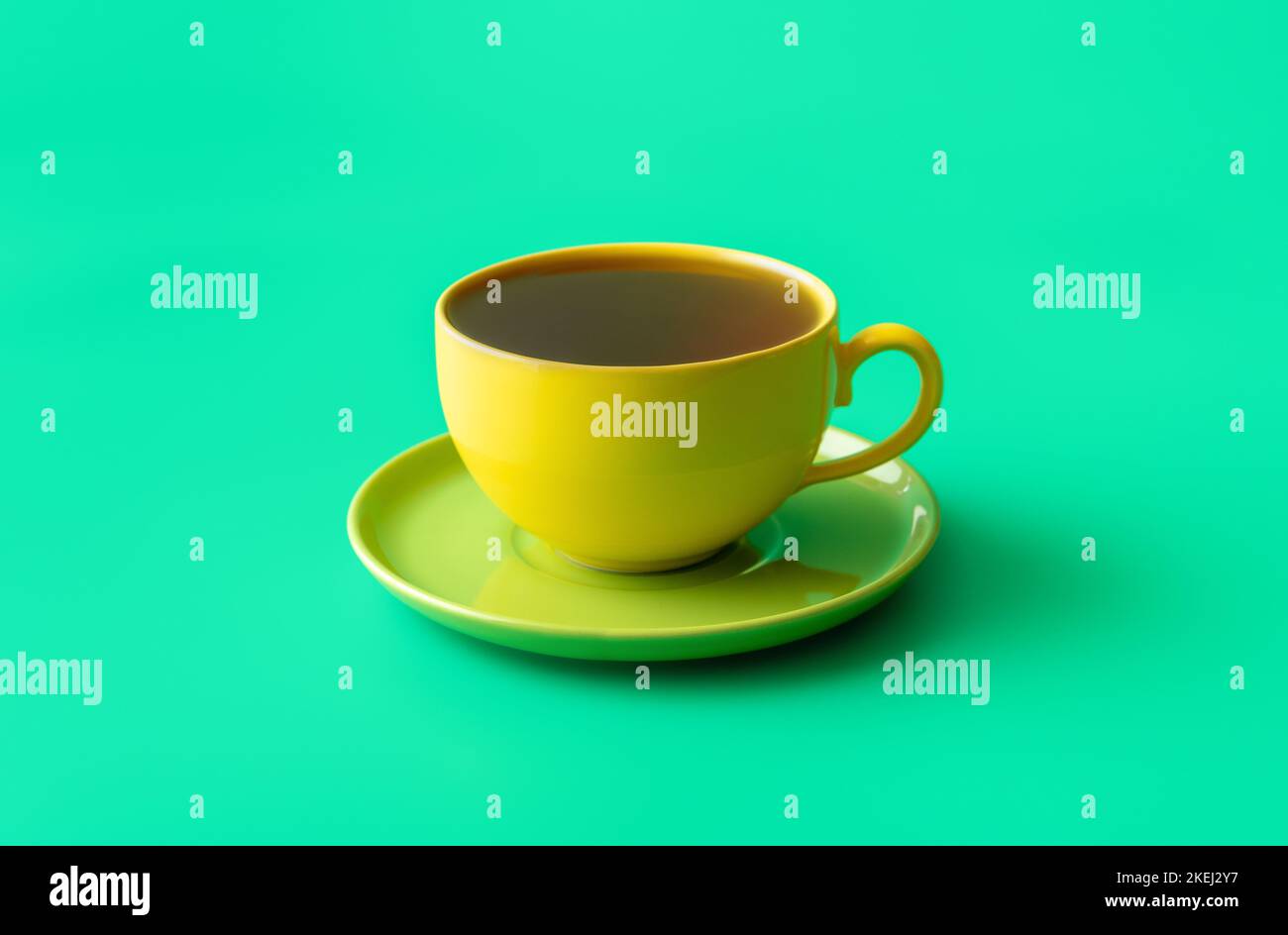 Close-up with a single cup of tea minimalist on a green colored table. Healthy hot drink, mint tea in a ceramic yellow cup Stock Photo
