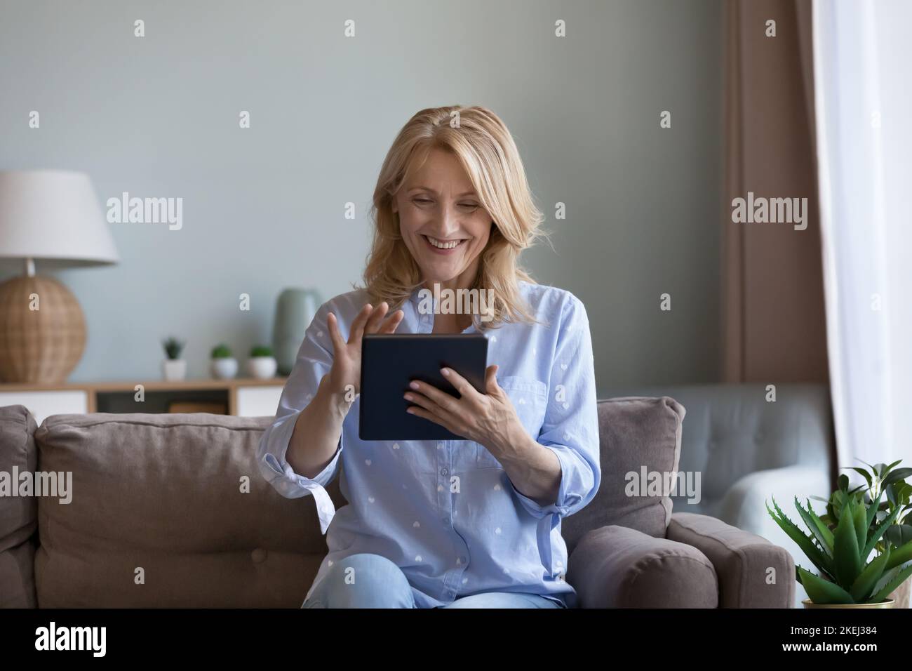 Happy mature woman using digital tablet at home Stock Photo