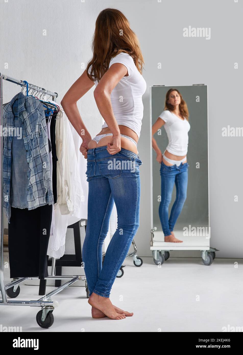 I like these already. an attractive young woman trying on jeans in a ...
