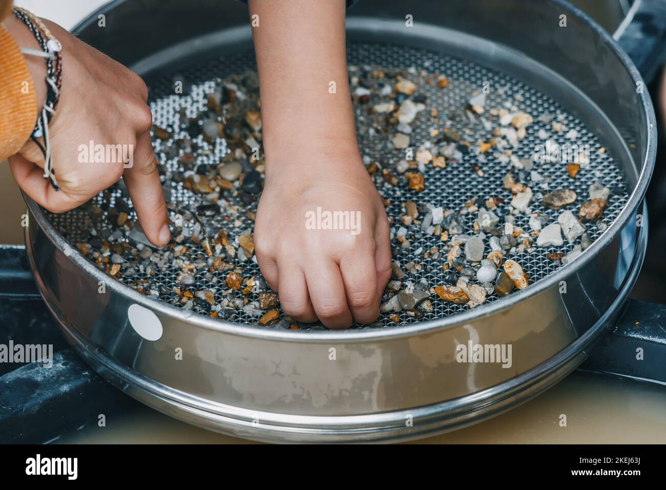 Child hand picking pebbles at the sieve at archaeological excavations ...