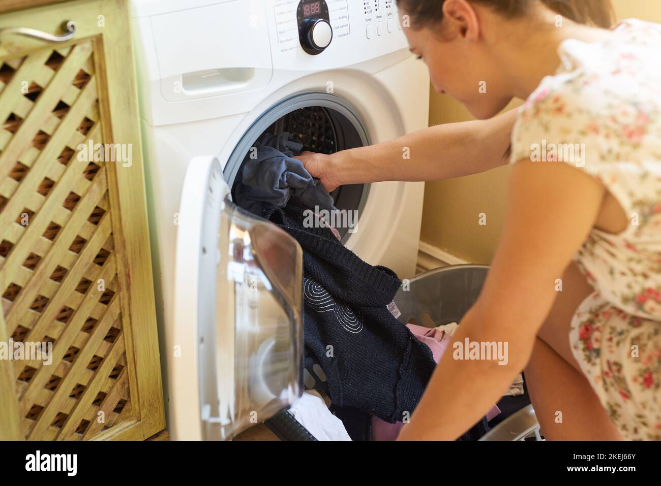 Laundry day. a young woman using a washing machine at home. Stock Photo