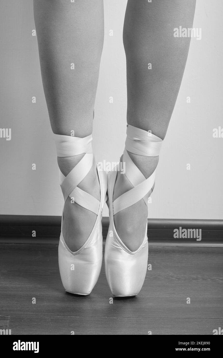 female ballerina feet in pointes on a wooden floor closeup image, monochrome Stock Photo