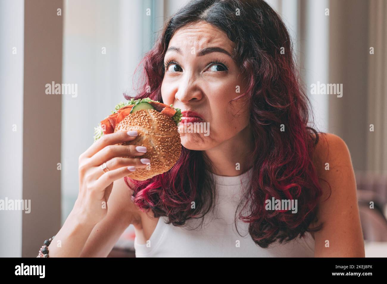 A girl sniffs a spoiled burger. Fast food diet and food poisoning