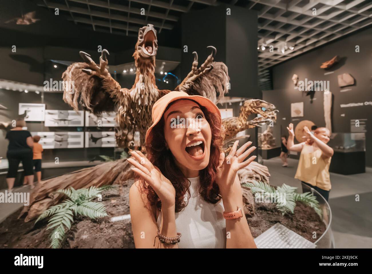 26 July 2022, Munster Natural History Museum, Germany: Excited and emotional girl visitor to the natural history museum with a feathered velociraptor Stock Photo