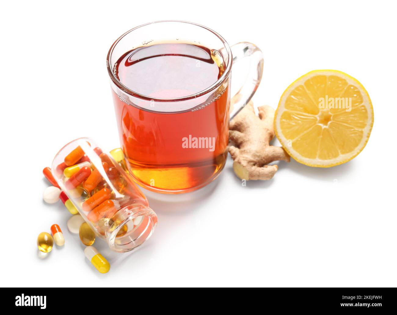 Pills for sore throat, glass cup of tea, ginger and lemon on white