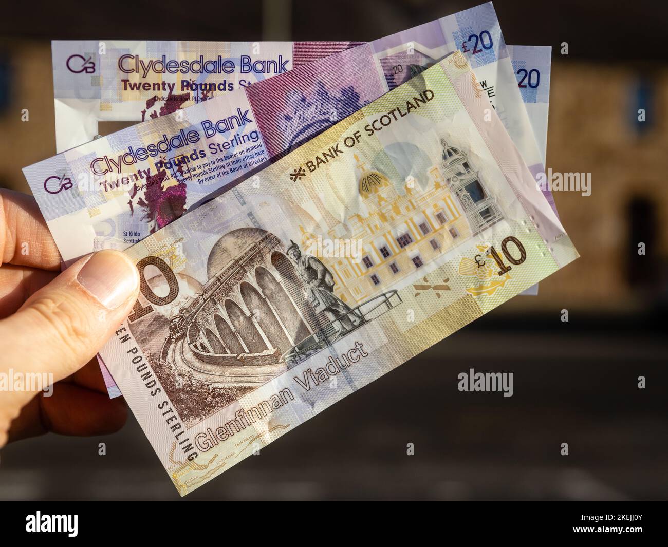Ten and Twenty Pounds Sterling paper currency from the Bank of Scotland were held in a mans left hand. Stock Photo