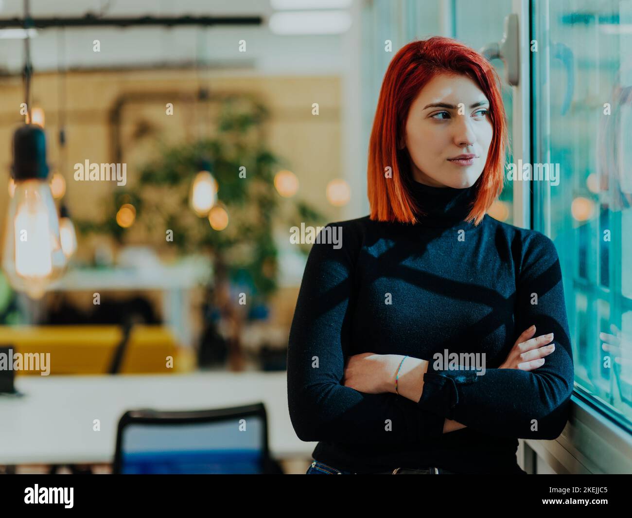 Headshot portrait of a modern woman with crossed arms in the office at