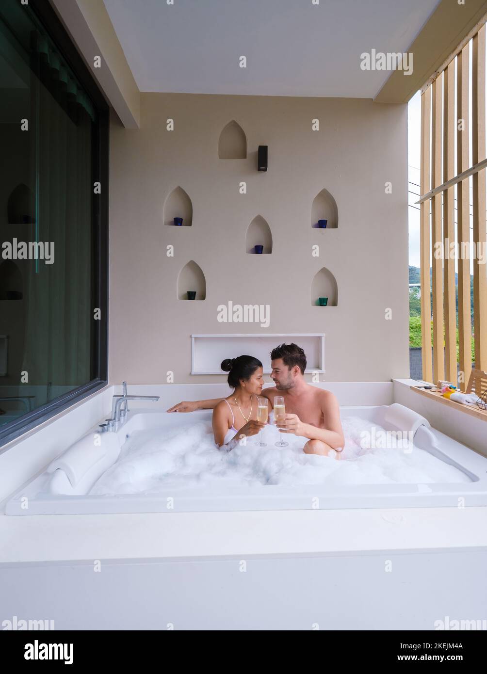couple drinking champagne in a jacuzzi during honeymoon vacation, Asian Thai women and caucasian