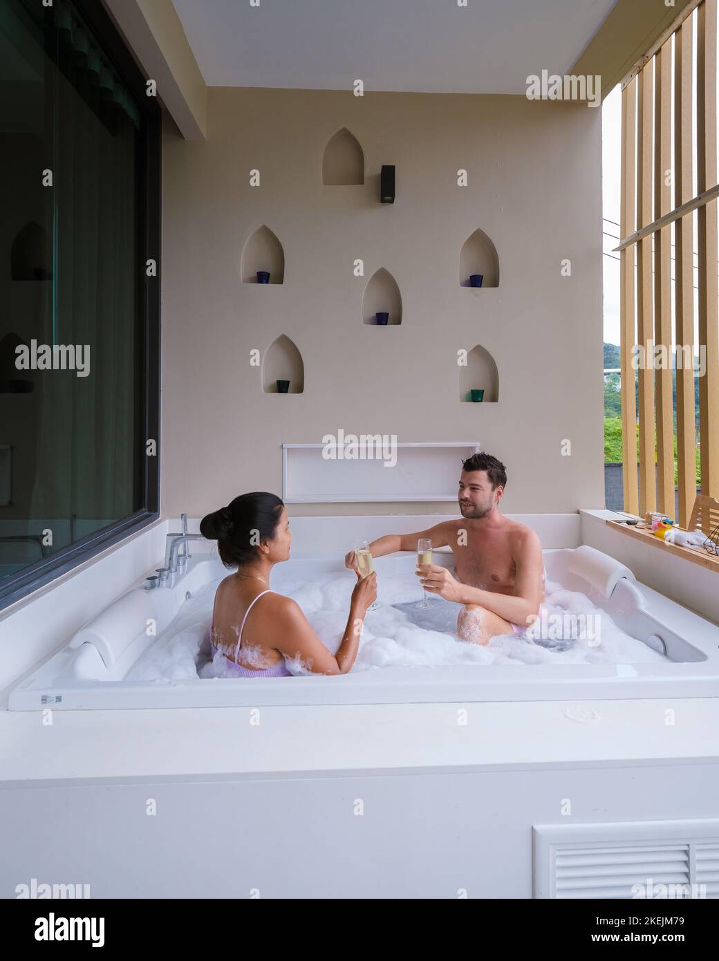 couple drinking champagne in a jacuzzi during honeymoon vacation, Asian ...