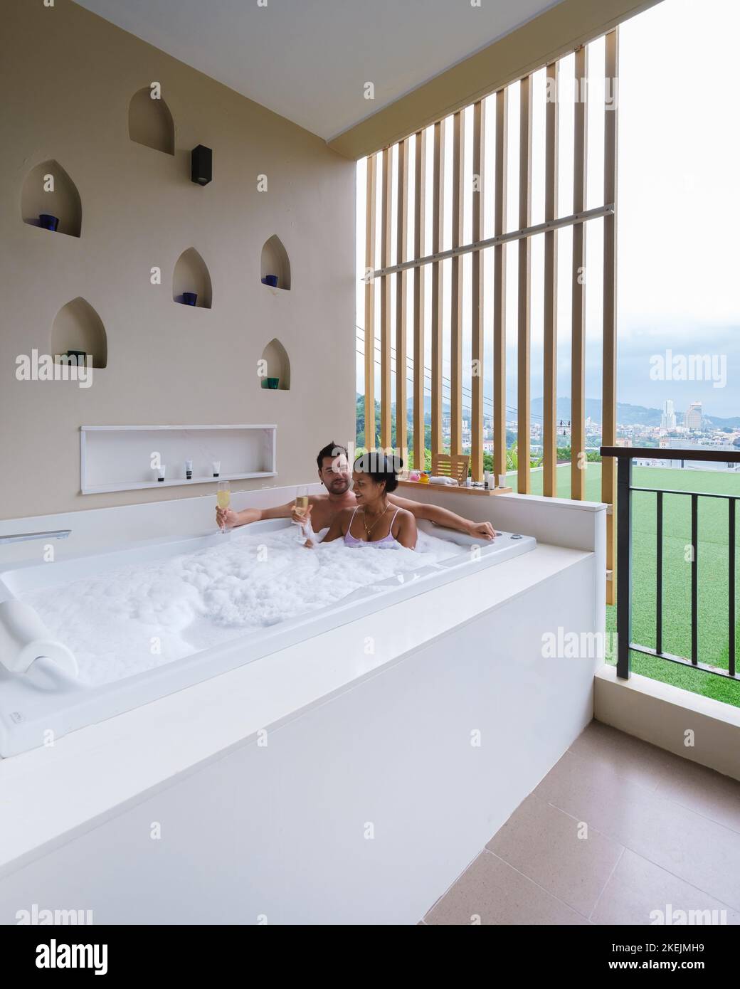 couple drinking champagne in a jacuzzi during honeymoon vacation, Asian Thai women and caucasian