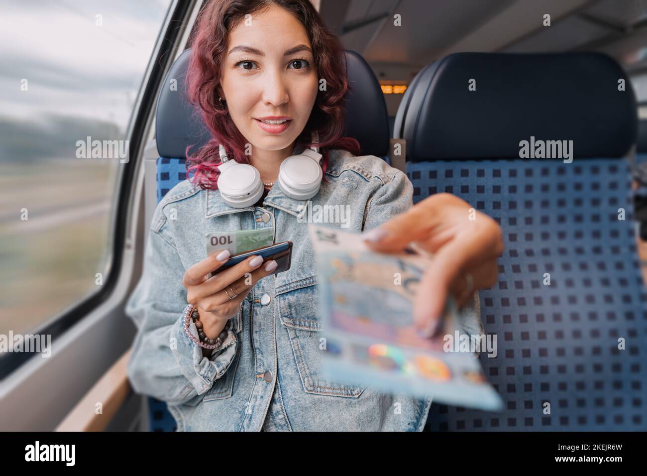 A girl on a public transport train passes euro banknotes to a stranger. The concept of credulity to fraud or scams Stock Photo