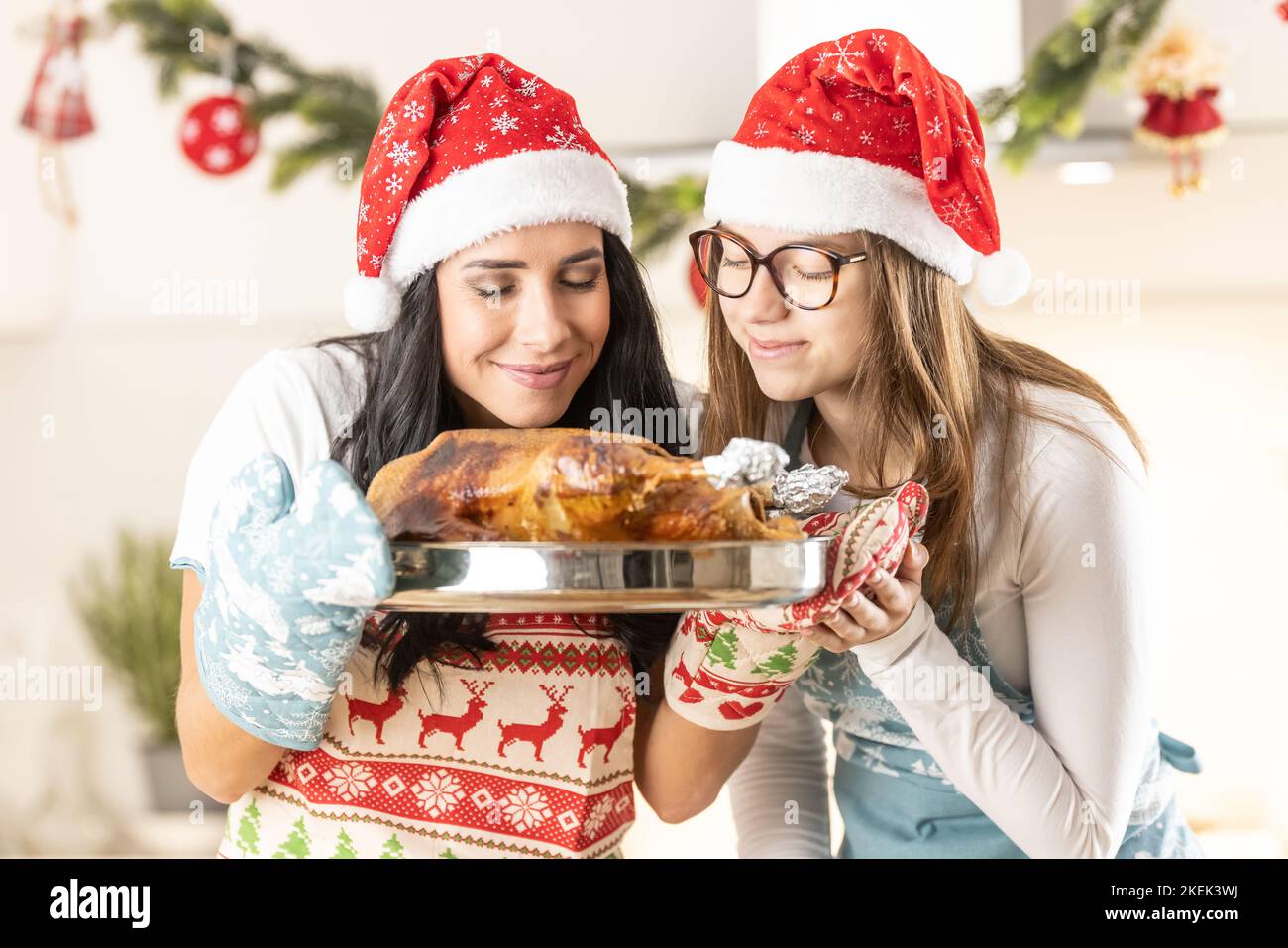 Two cheerful cooks, mom and her teenage daughter, in Christmas aprons ...