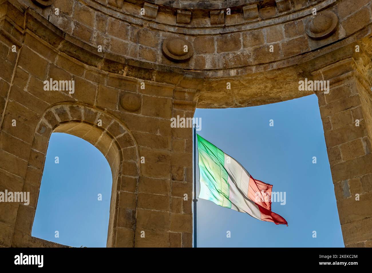 The Italian flag flutters next to the war memorial, historic center of Poppi, Arezzo, Italy Stock Photo