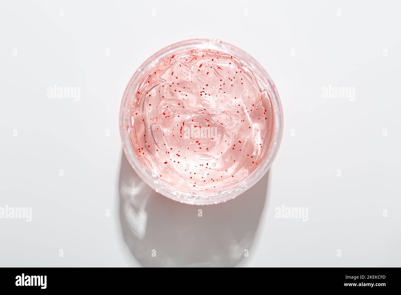 Top view of facial transparent gel with red exfoliating particles in jar on light surface Stock Photo