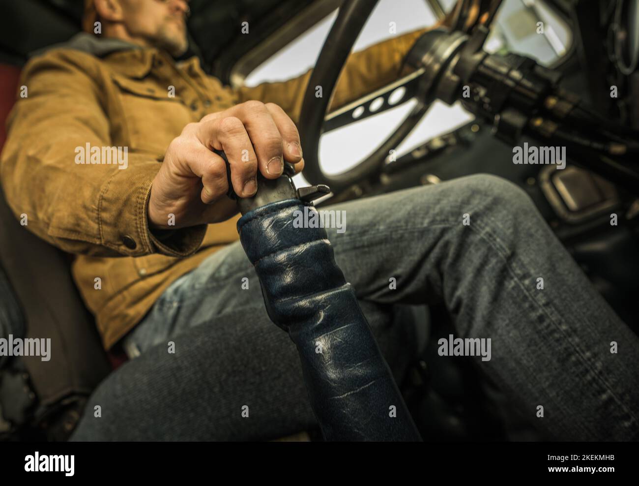 Manual Transmission Classic Semi Truck Driving. Caucasian Trucker Behind the Wheel. Heavy Duty Transportation Theme. Stock Photo