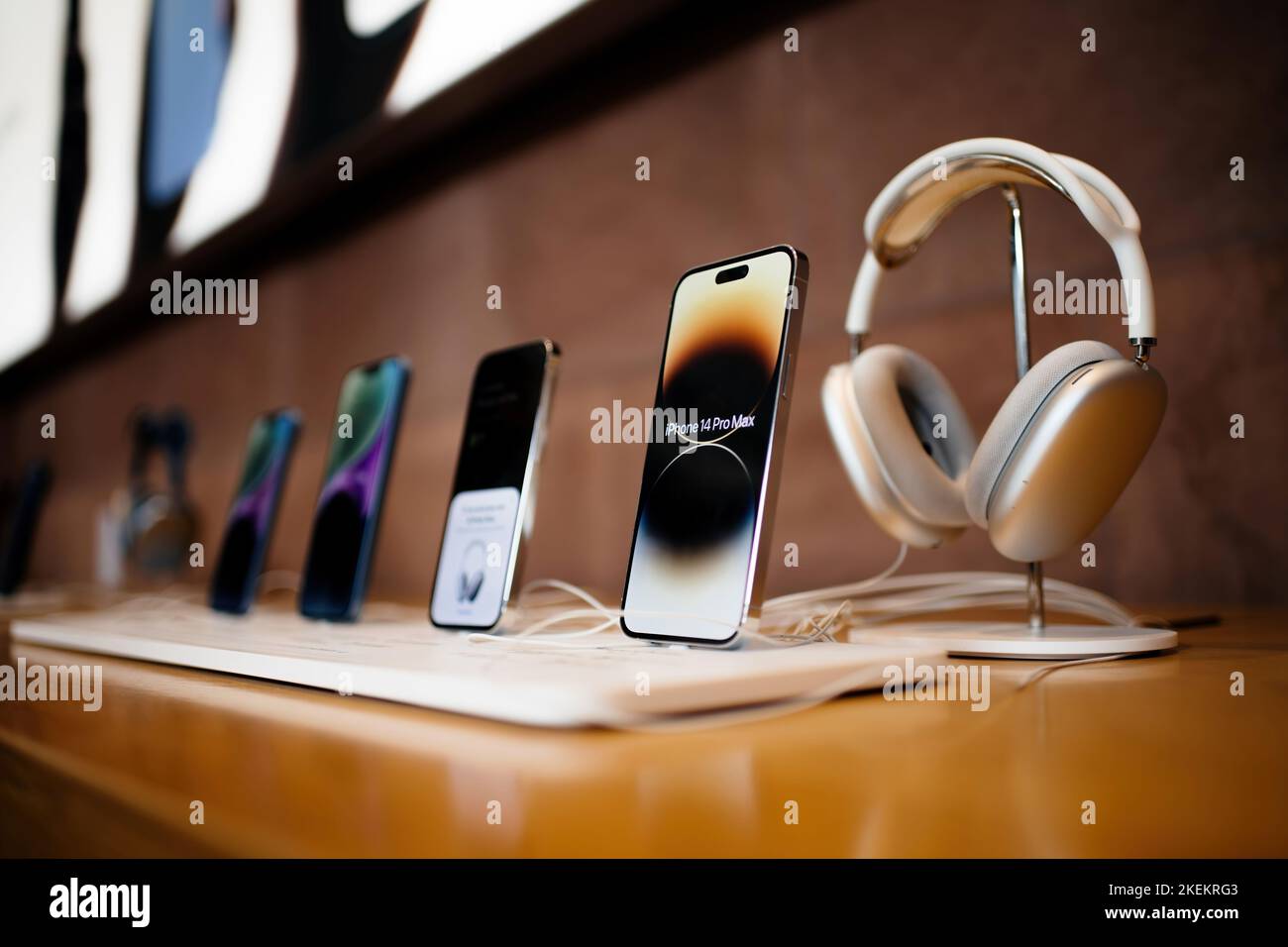 Paris, France - Oct 28, 2022: Row of all current line of Apple Computers iPhone smartphone - focus on 14 pro Max telephones with silver AirPods Max headphones Stock Photo
