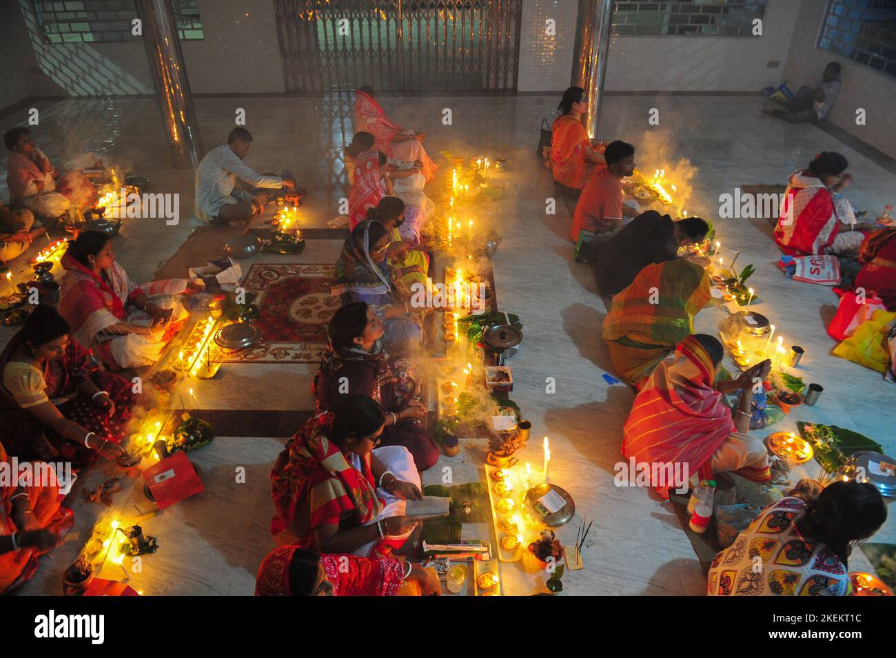 Hindu devotees sit together with lamps on the floor at Loknath Temple