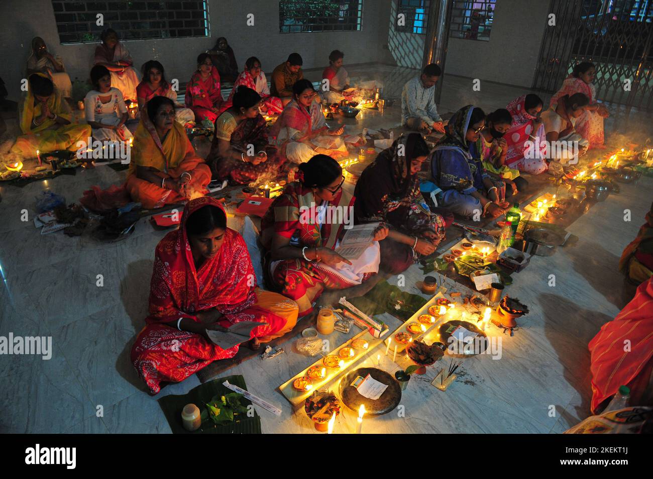Hindu devotees sit together with lamps on the floor at Loknath Temple