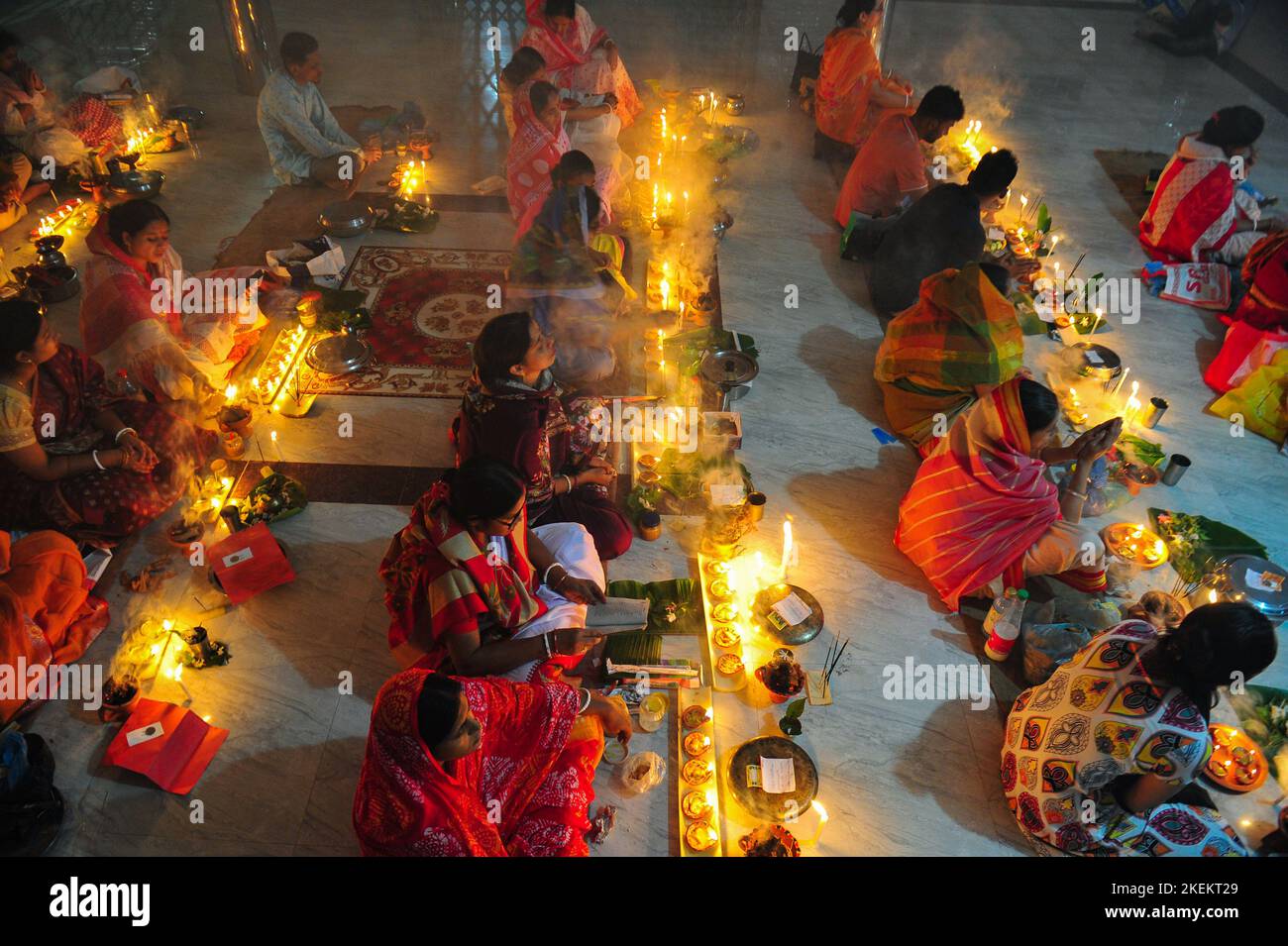 Hindu devotees sit together with lamps on the floor at Loknath Temple