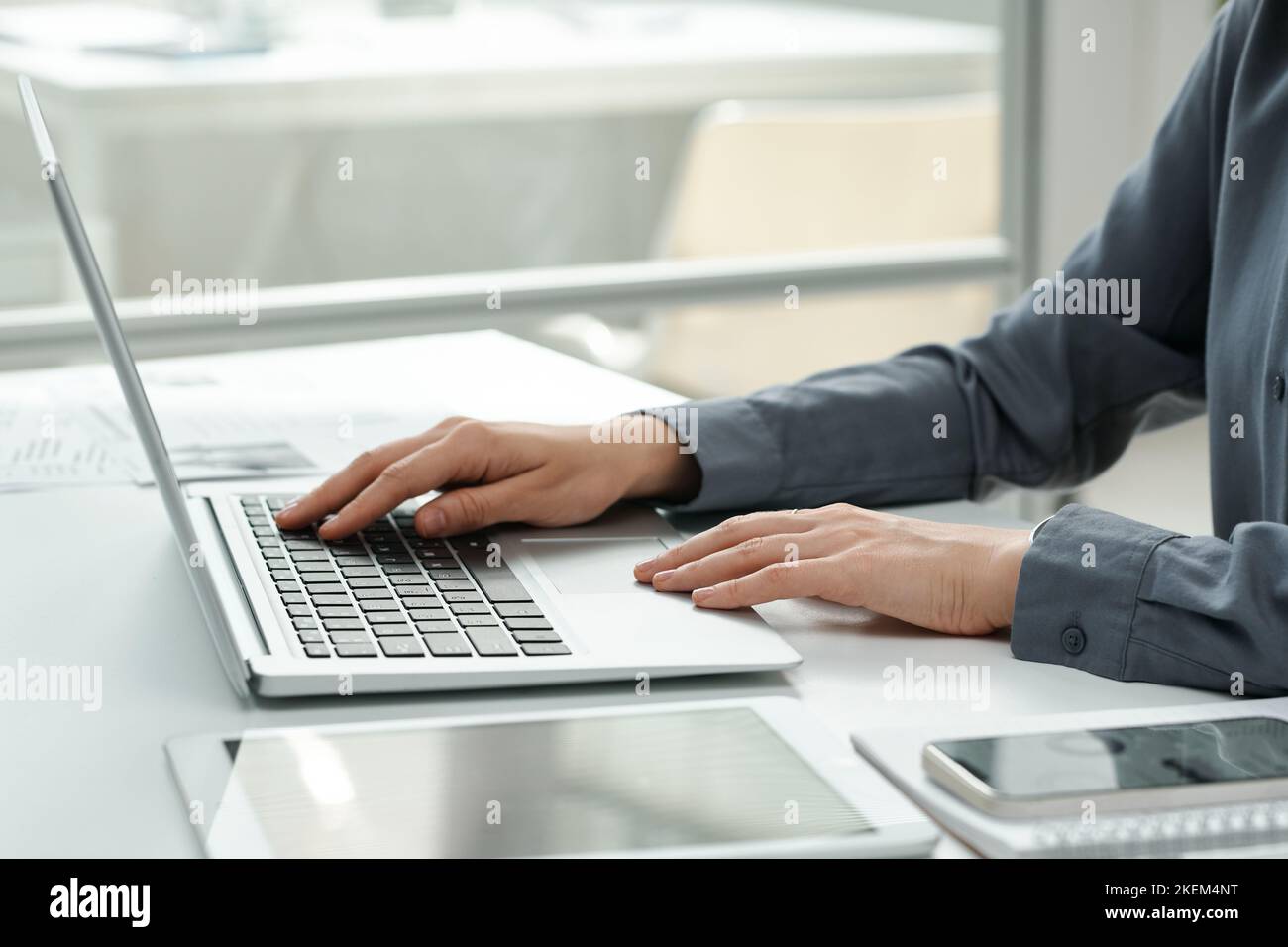Close-up of young businesswoman typing on laptop, doing her online work at her workplace at office Stock Photo