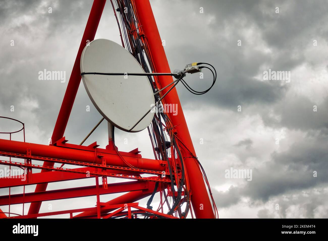 Part of communication tower with satellite dish against backdrop of dramatic sky with storm clouds. Telecommunication tower close-up.. Stock Photo