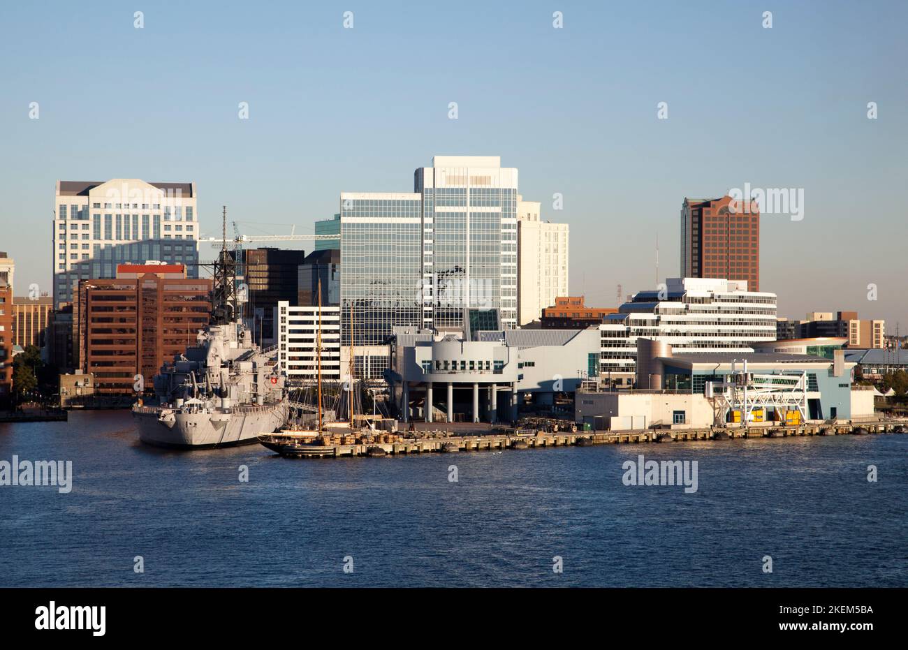 The evening view of Norfolk downtown skyline with moored military ship ...
