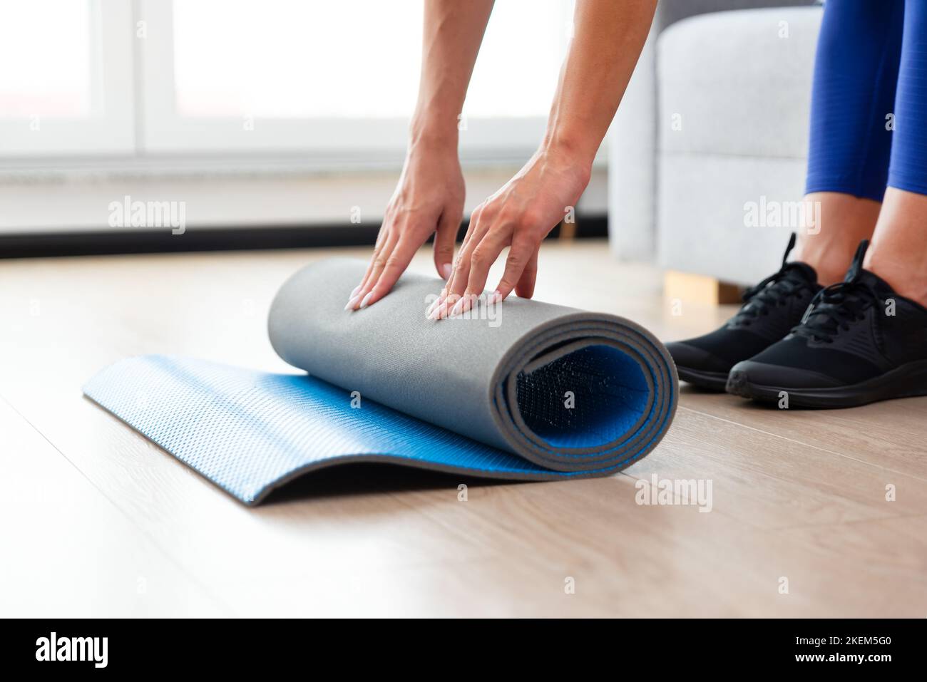Woman folding yoga mat, workout at home concept Stock Photo