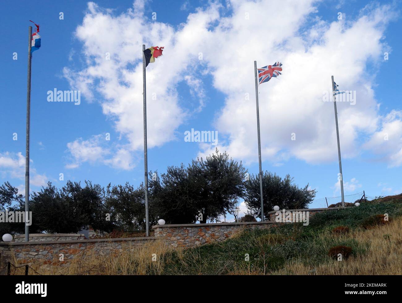 Tattered flags and flagpoles against a blue sky with scattered clouds. Stock Photo