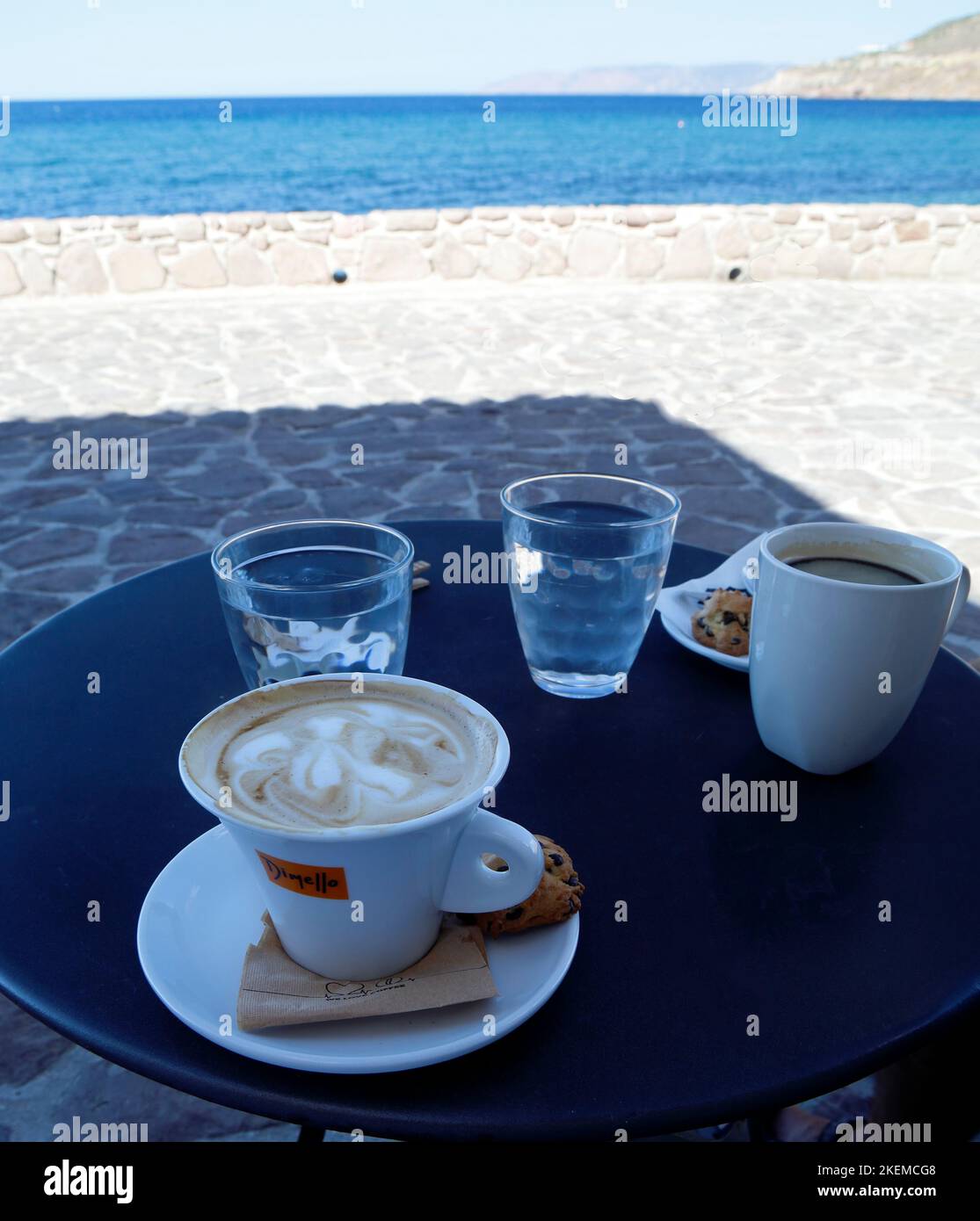 Capuccino coffee, black coffee, water glasses on a small table outdoors by the sea. Greek island. Autumn. October 2022. cym Stock Photo