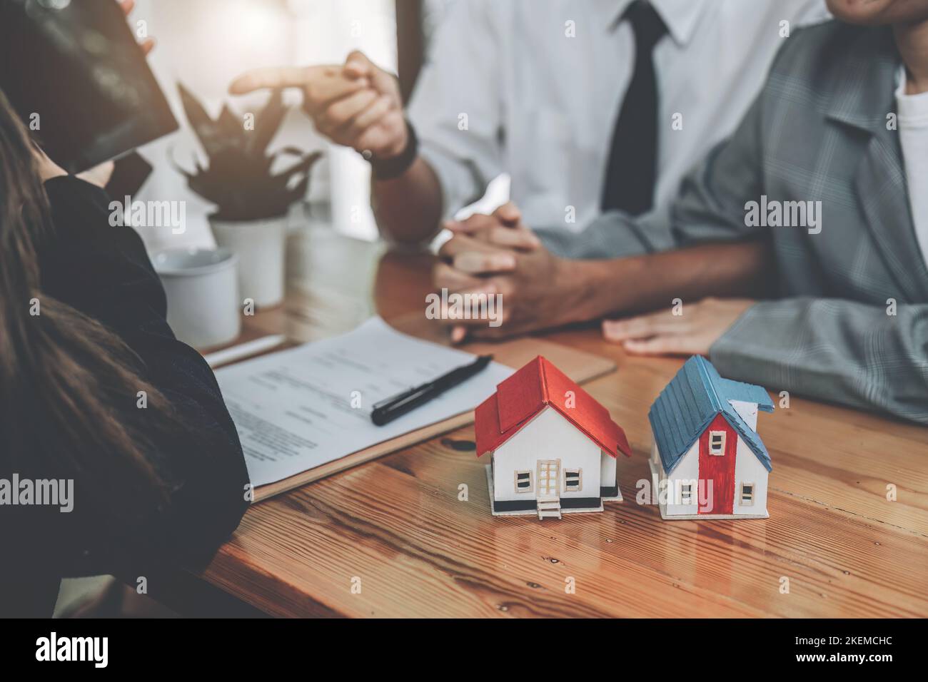 Bank officer, real estate employee talking to spouse, see information in Tablet computer about interest rates for home loan in the office, loan Stock Photo