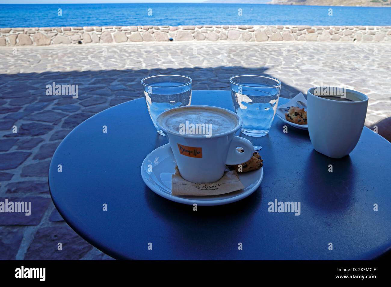 Capuccino coffee, black coffee, water glasses on a small table outdoors by the sea. Greek island. Autumn. October 2022. cym Stock Photo