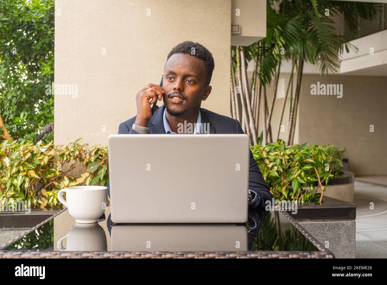 Portrait of handsome black African businessman wearing suit and using laptop computer Stock Photo