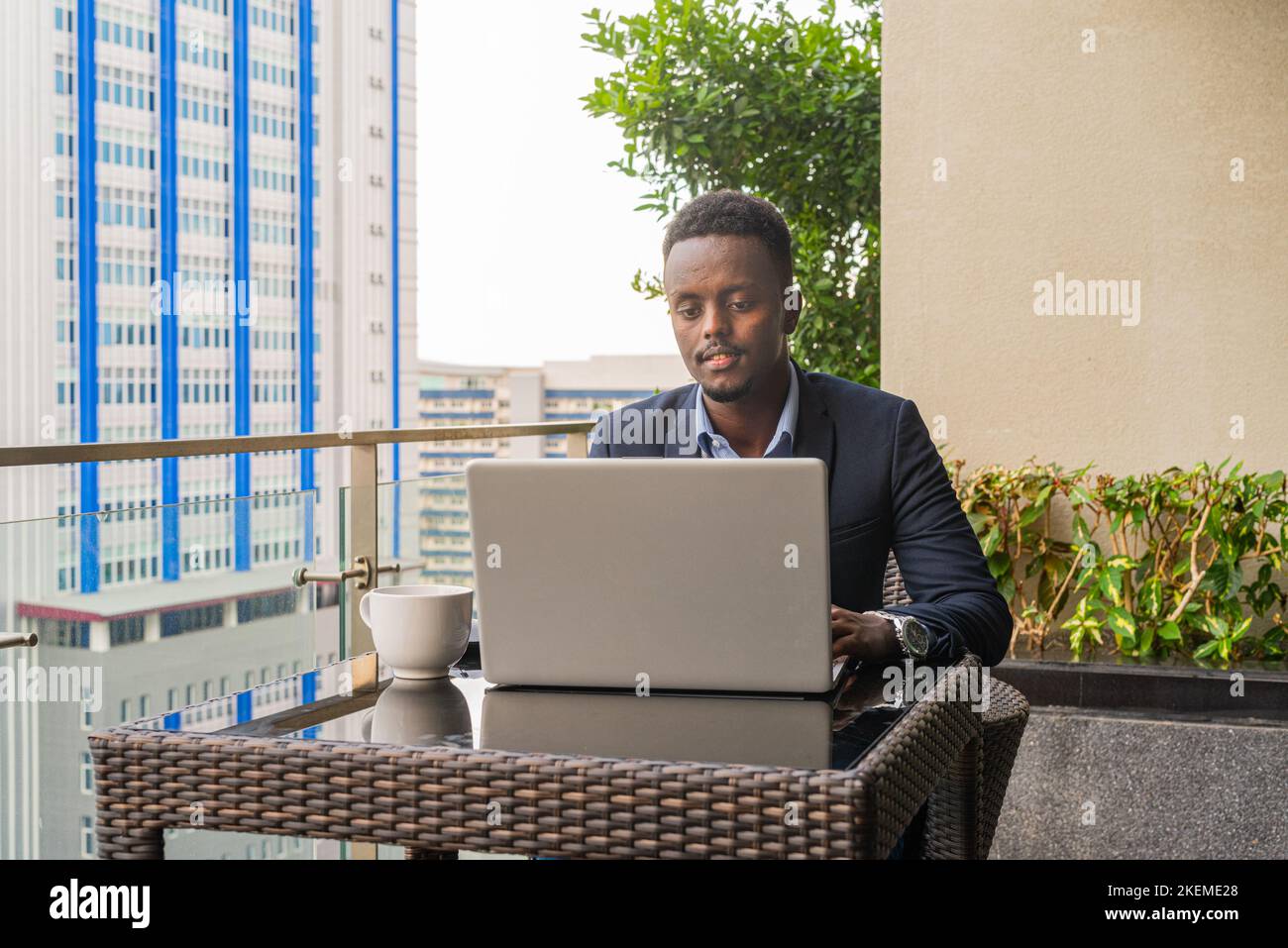Portrait of handsome black African businessman wearing suit and using laptop computer Stock Photo