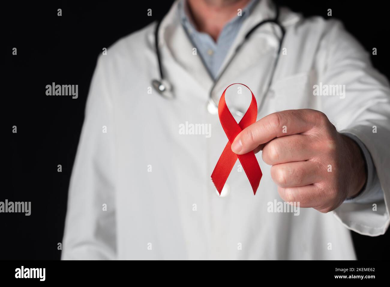 Doctor showing a red ribbon, symbol of World AIDS Day. Support from health personnel to people