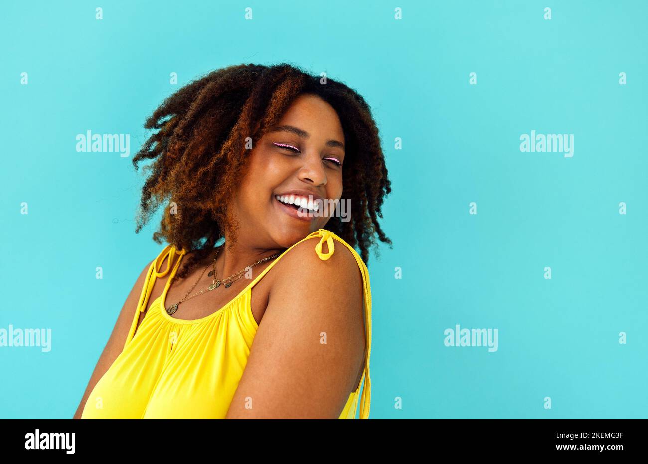 Beautiful bright joyful african woman in yellow dress in blue studio ...