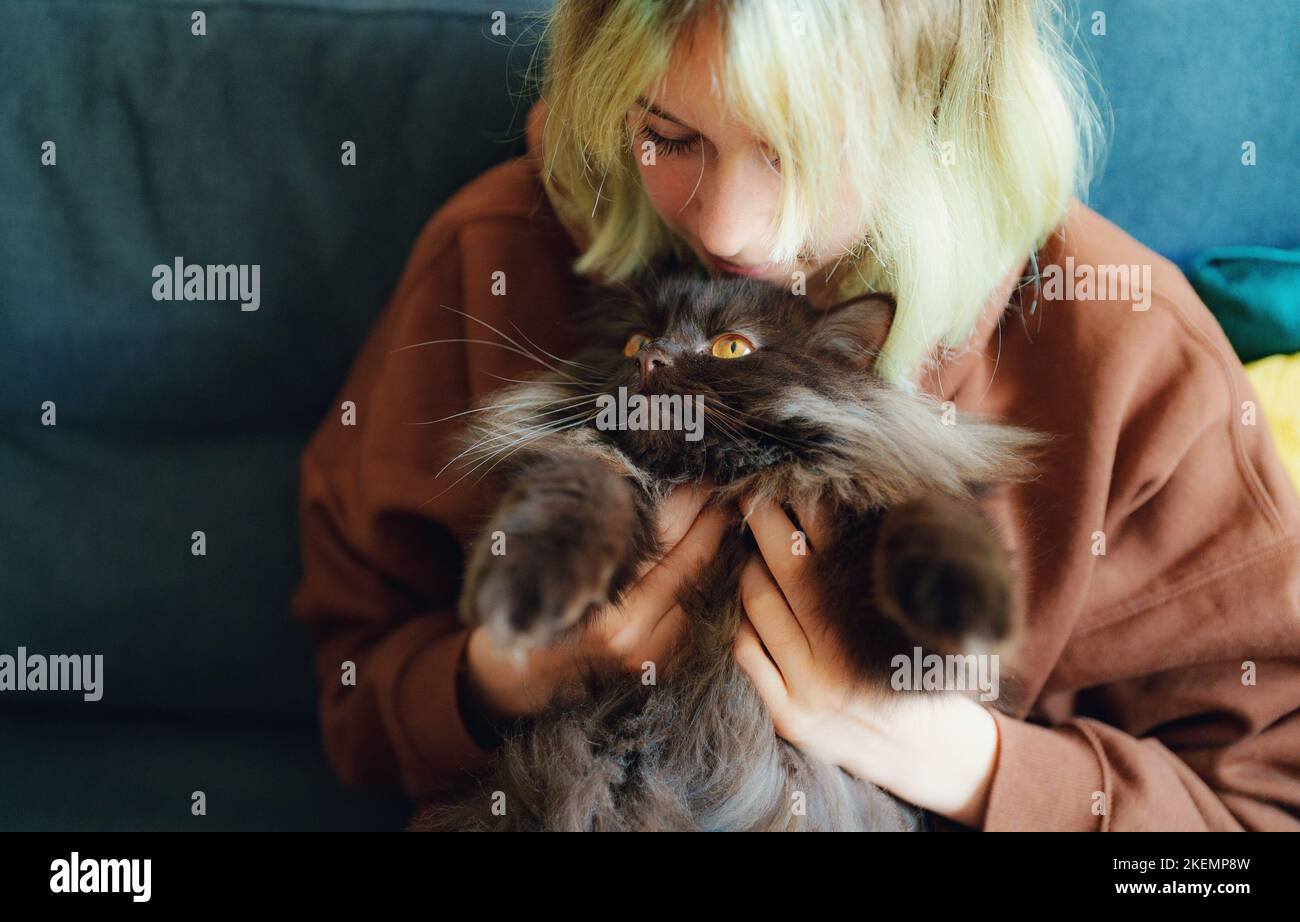 Teenage girl hugging cat at home. Stock Photo