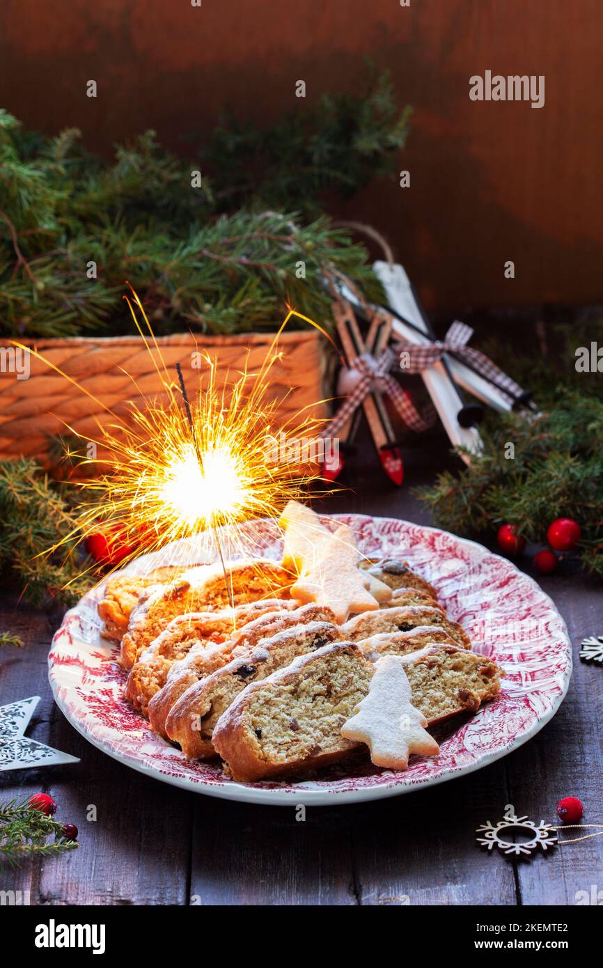 Christmas stollen with dried fruits, nuts and spices, Christmas decorations on a dark wooden background. Rustic style. Stock Photo