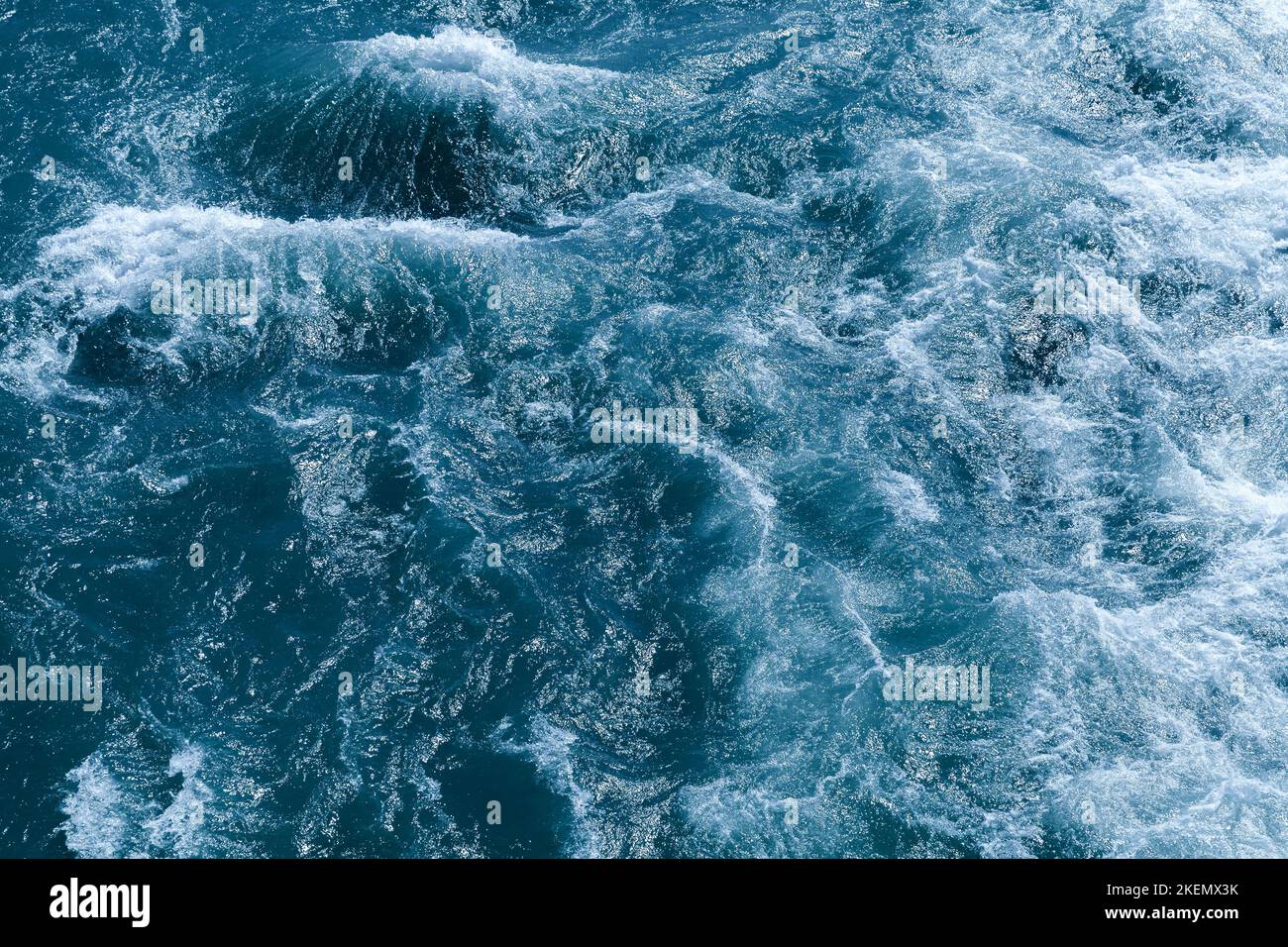 Stormy deep blue ocean water with waves and foam, top view, natural
