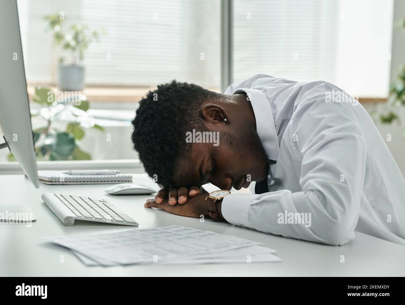 African American tired businessman sleeping at workplace in front of computer at office Stock Photo