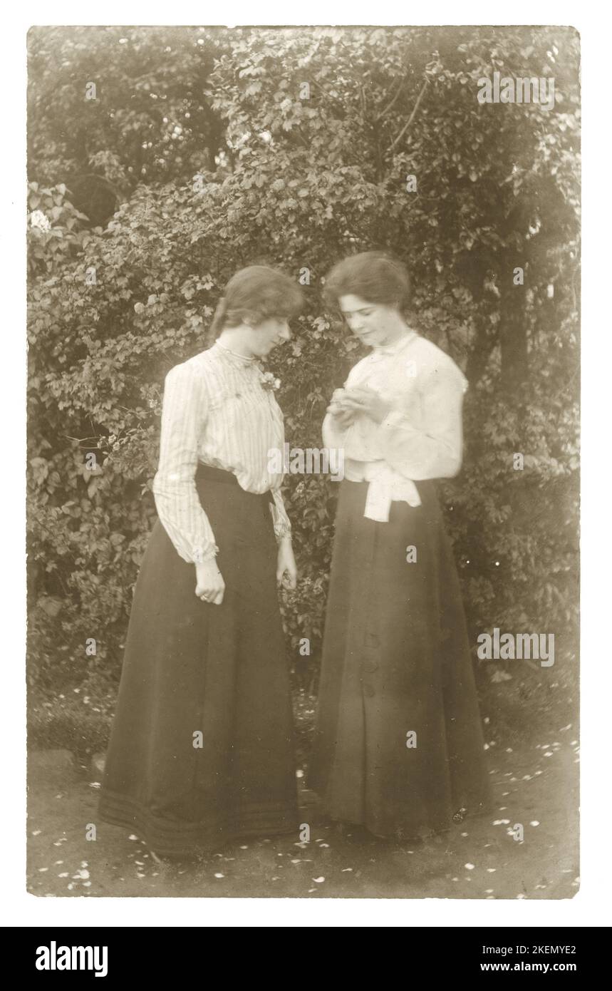 Original WW1 era postcard amateur photograph of 2 young women, looking at a rose, ghostly image, circa 1914, U.K. Stock Photo