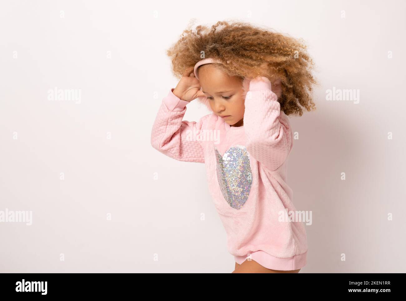 Happy cute child girl with curly hair in pink dress standing isolated ...