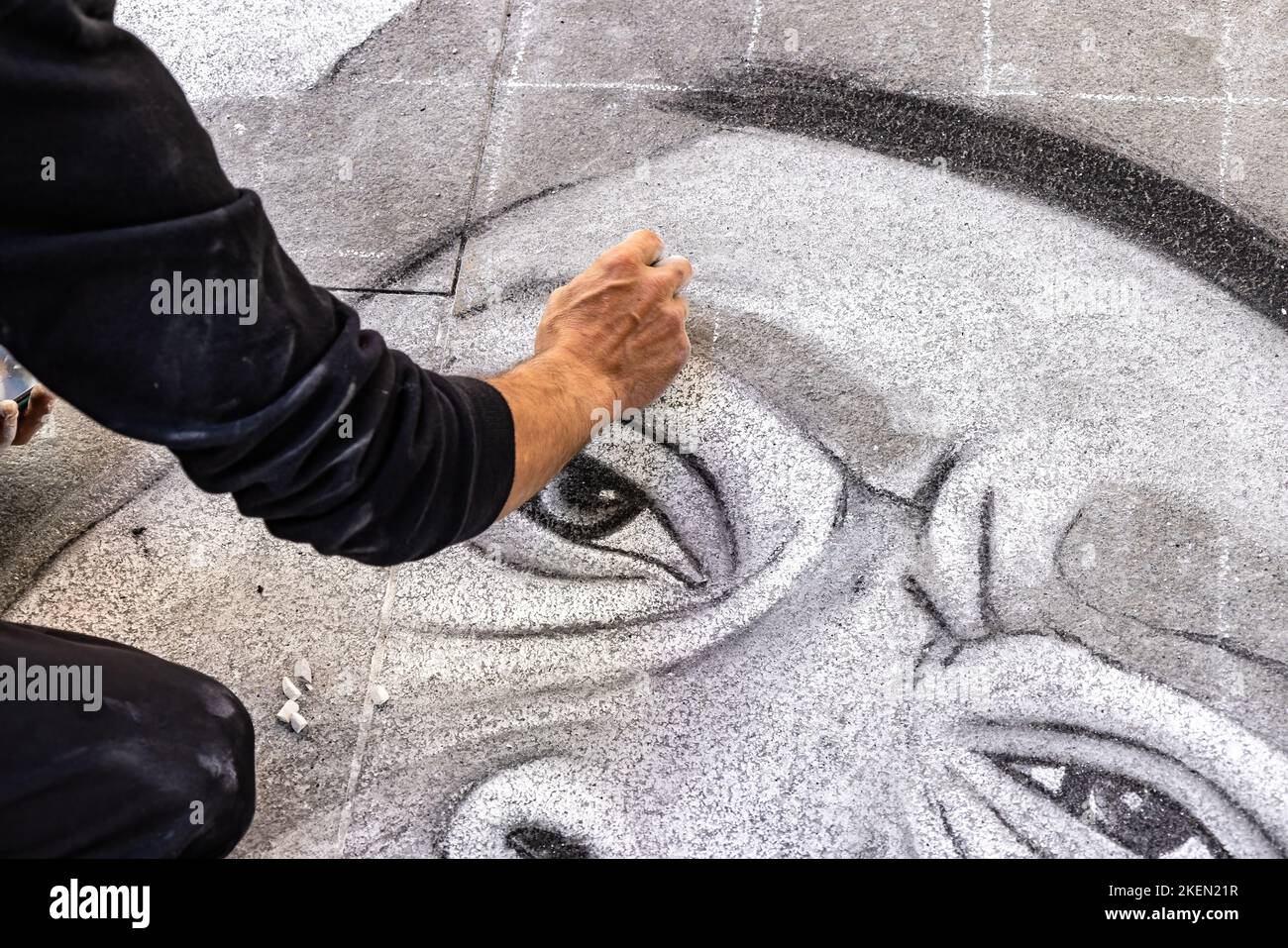 Blurred hand by movement of a street artist painting with chalk in the pavement Stock Photo
