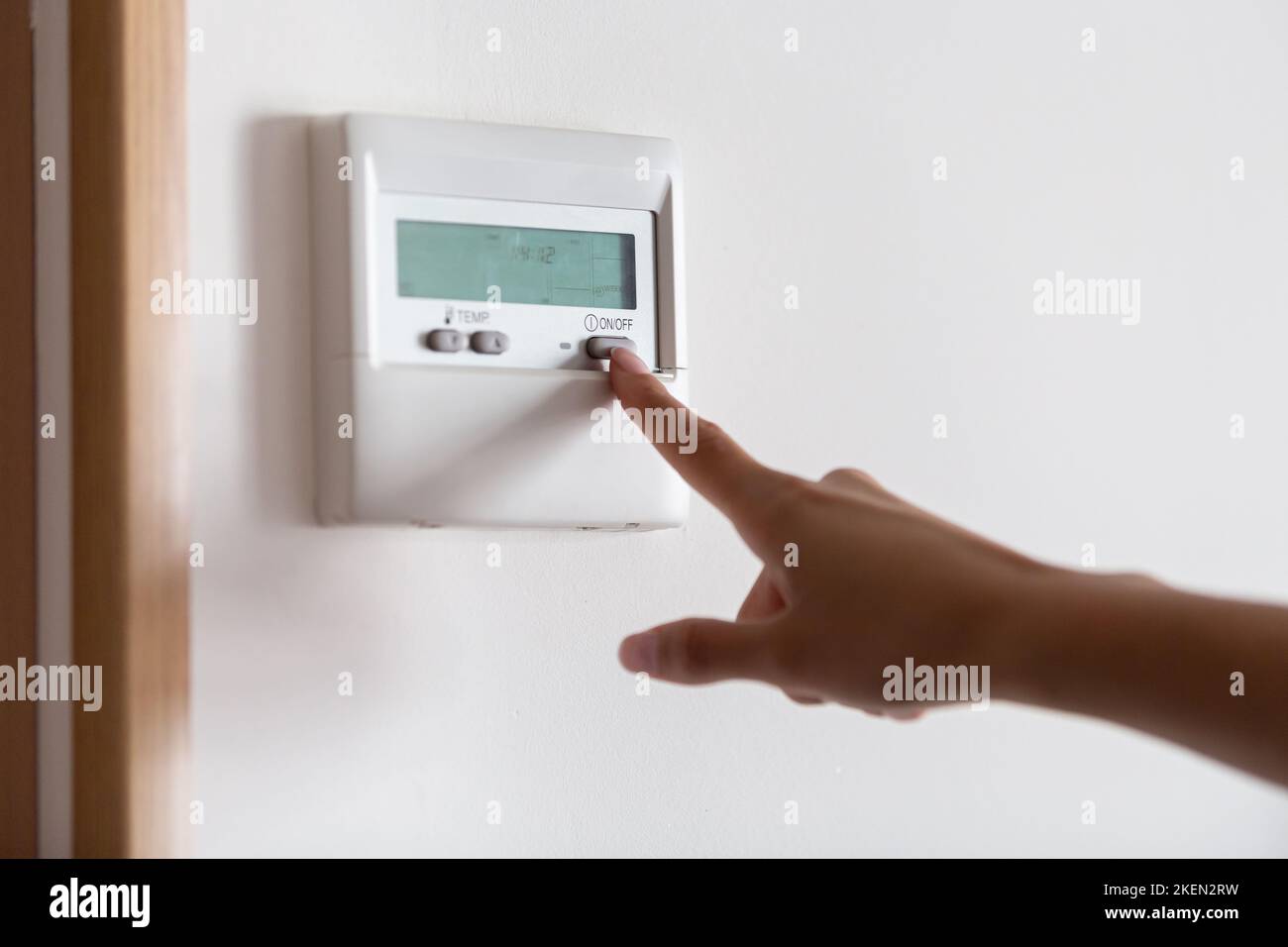Close-up of a young woman's hand pressing the on/off button of the air conditioner or heater Stock Photo