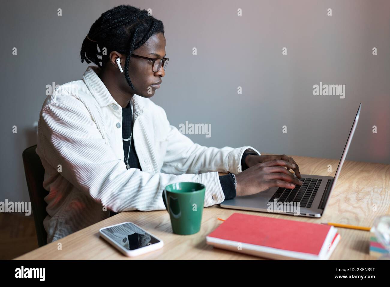 Young focused African American man sits at wooden table with laptop ...