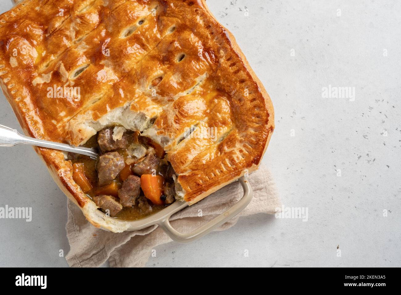 English beef steak pie with crispy puff pastry closeup in a baking