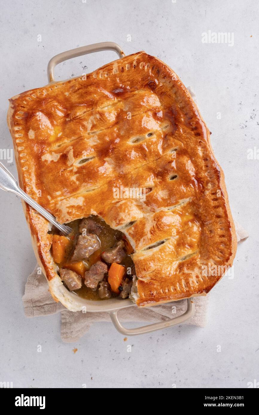 English beef steak pie with crispy puff pastry closeup in a baking