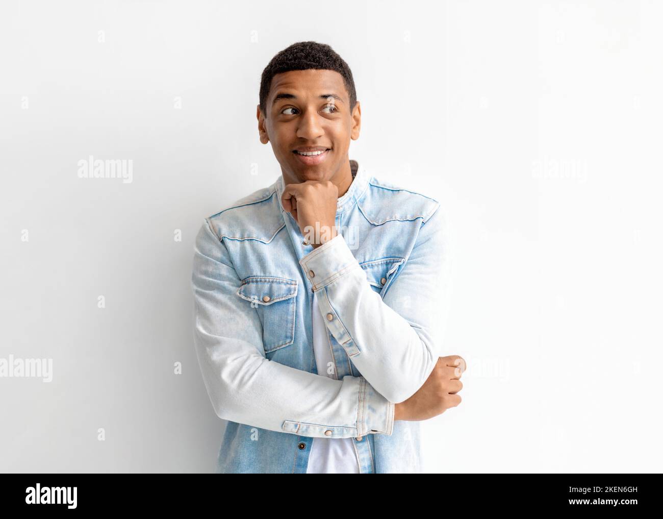 Portrait of young smiling African American man in a denim shirt looking away and thinks about something Stock Photo
