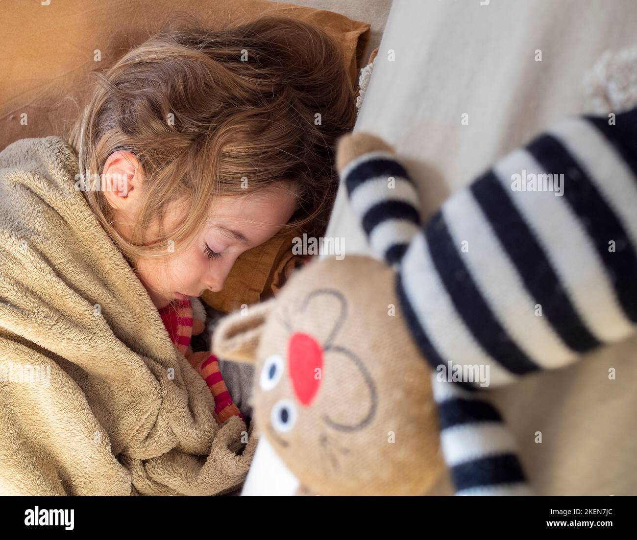 Adorable little girl sleeps on the couch next to her favorite stuffed